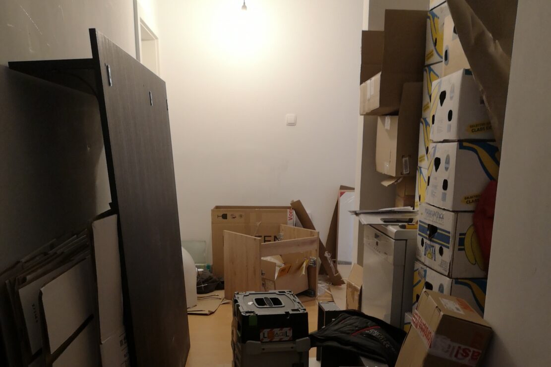 Ein Gang einer Wohnung, vollgestellt mit Kartons und Werkzeug