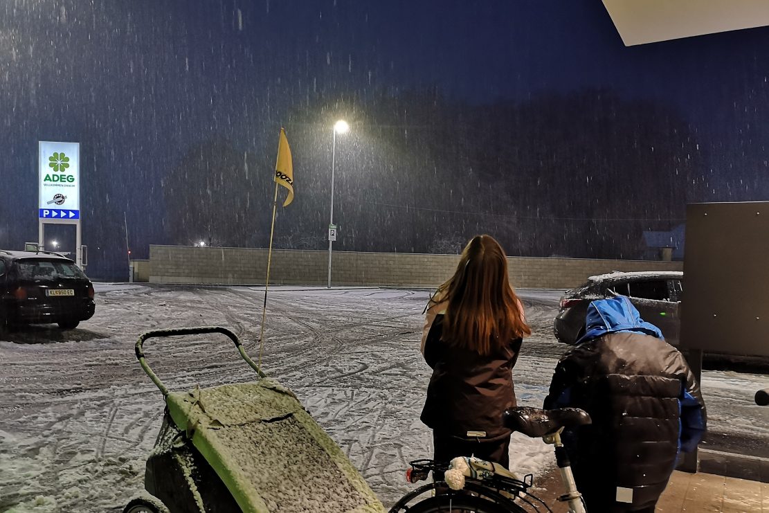 Zwei Kinder am Adeg-Parkplatz bewundern den abendlichen Schneefall.